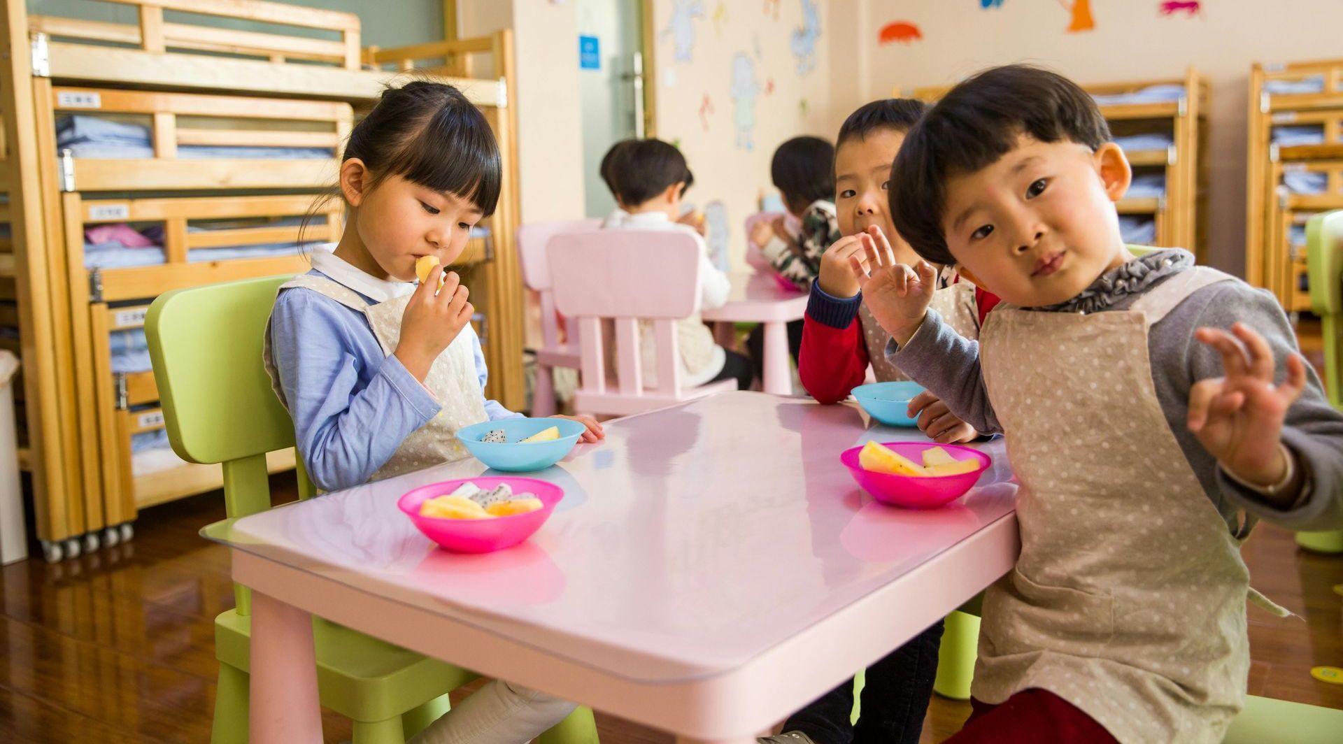 A group of children are sitting at a table eating food.