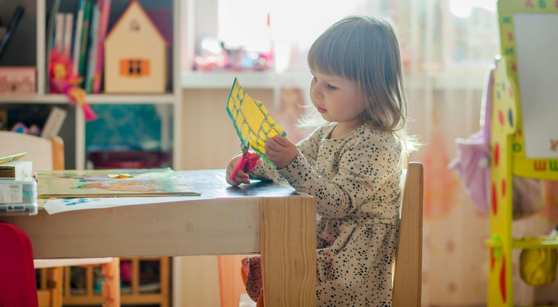 A little girl is sitting at a table playing with a toy.
