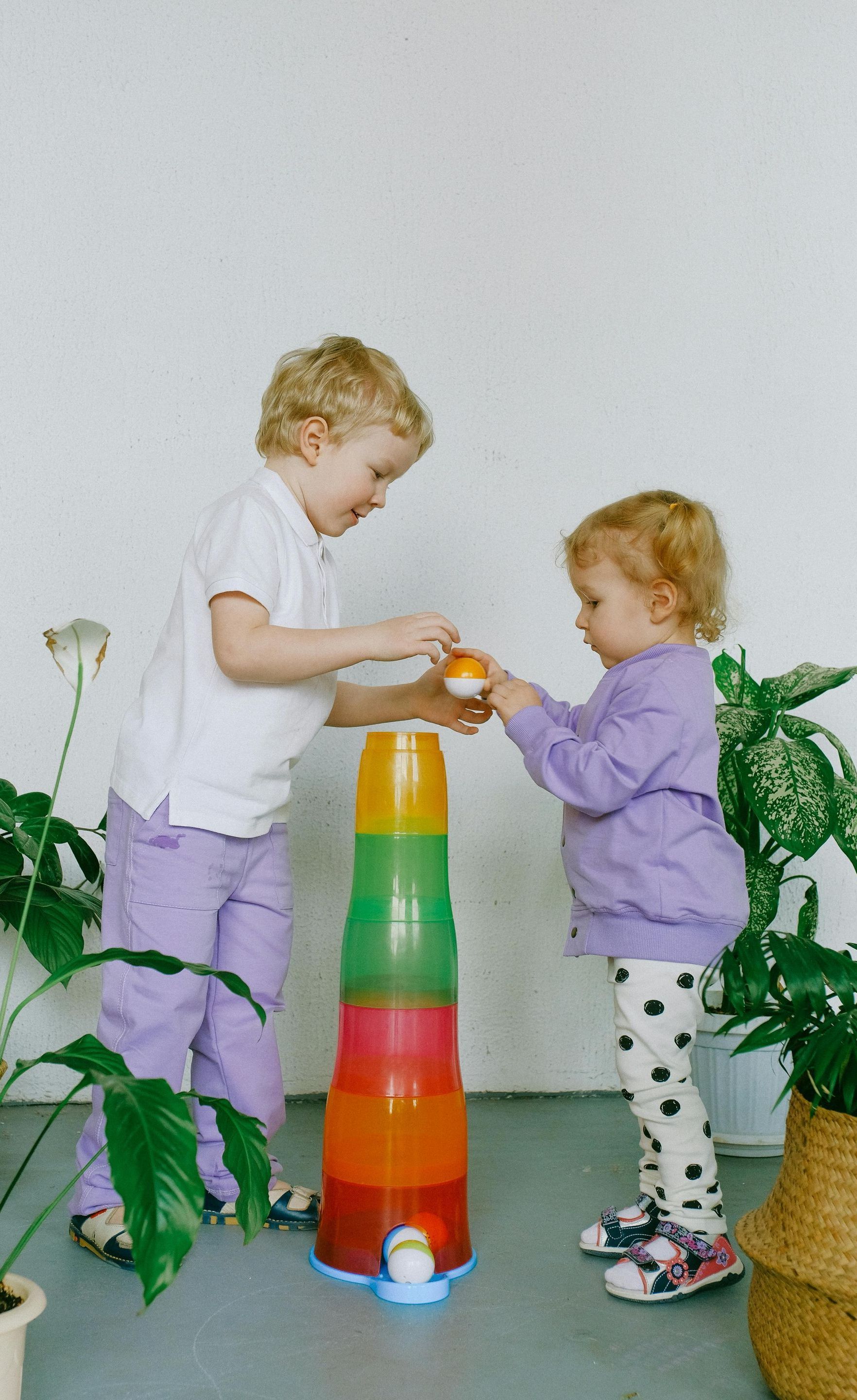 Two children are playing with a stack of cups.
