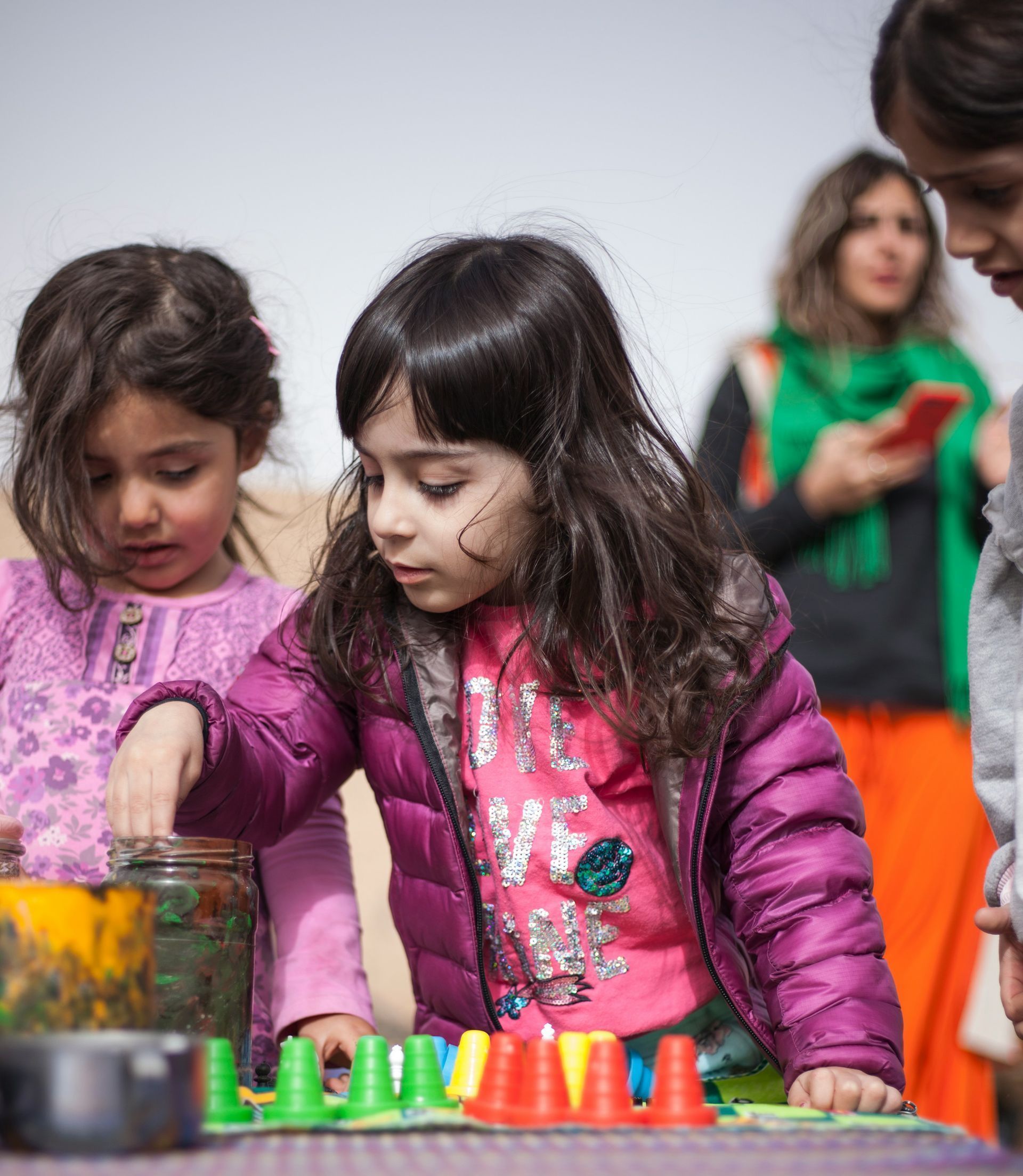 A group of young girls are playing with toys on a table.