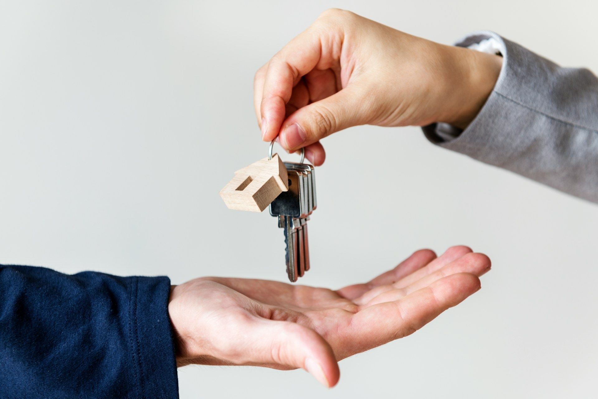 Person handing house keys to another person.