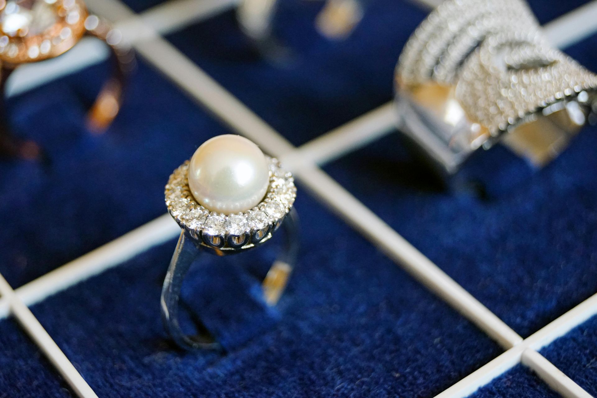 Pearl ring with surrounding diamonds on display.