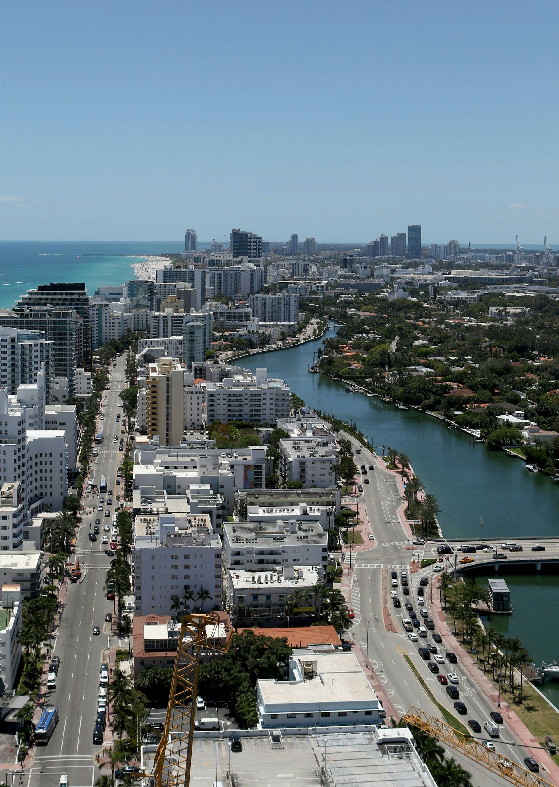 Aerial view of Miami Beach, Florida, with ocean, buildings, waterway, and clear blue sky.