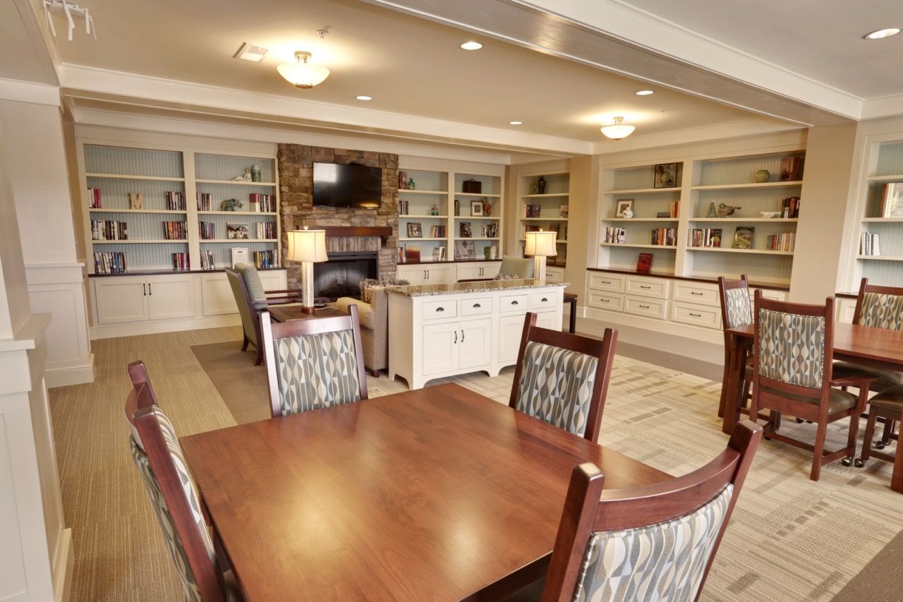 Interior community lounge with built-in bookshelves, a stone fireplace, and seating.