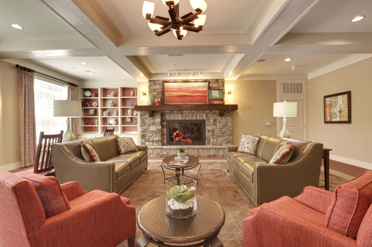 Cozy community lounge with a stone fireplace, couches, and built-in shelves.