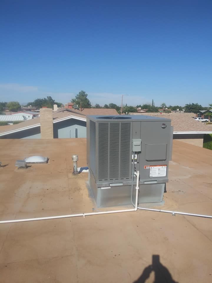 HVAC unit on a flat roof under a blue sky, with visible piping.
