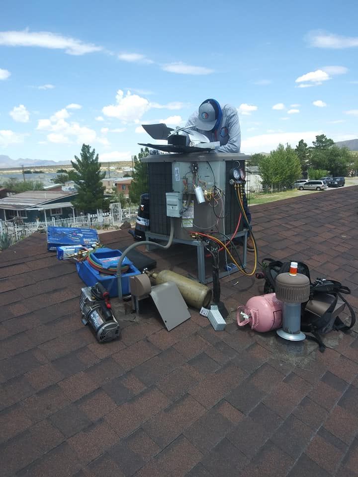 HVAC technician working on rooftop air conditioning unit, surrounded by tools and equipment under a sunny sky.