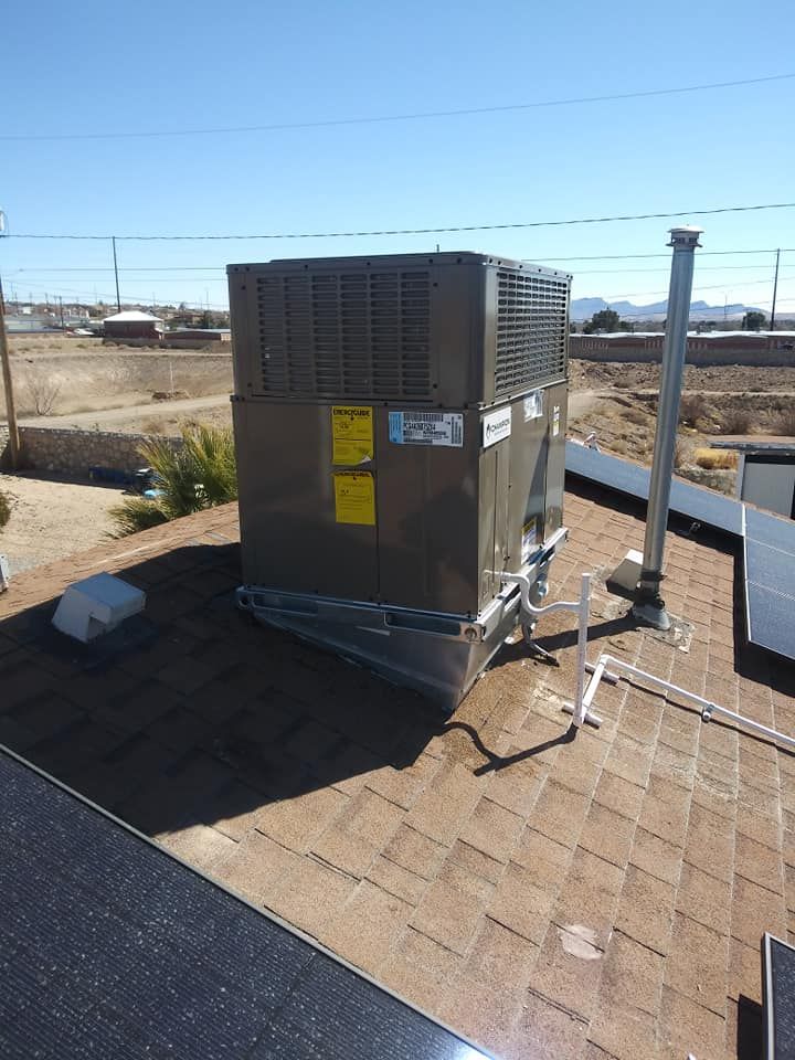 Rooftop HVAC unit with solar panels, blue sky. Grey and brown tones.