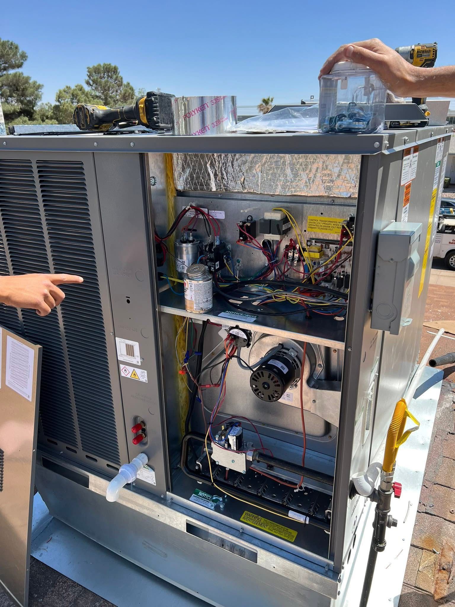 HVAC unit with open panel, two people working on it outdoors.