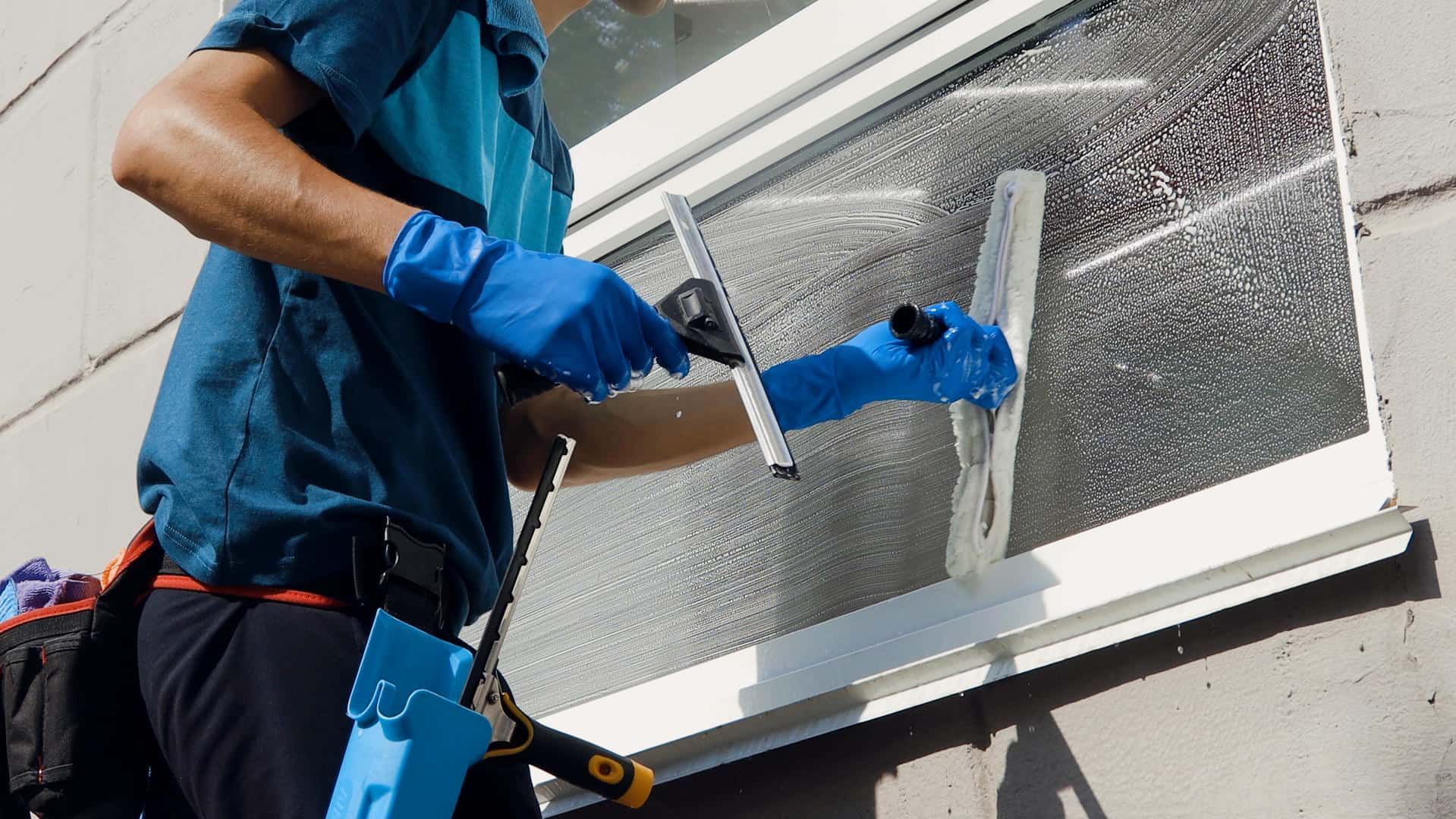 A man is cleaning a window with a squeegee.