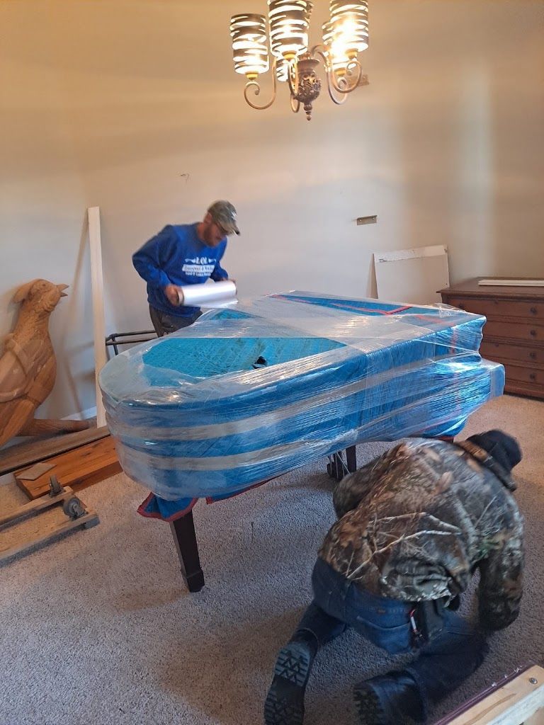 Workers moving a blue-wrapped couch in a living room during a move