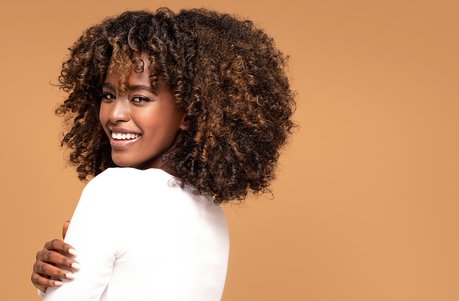 A woman with red curly hair is smiling for the camera.