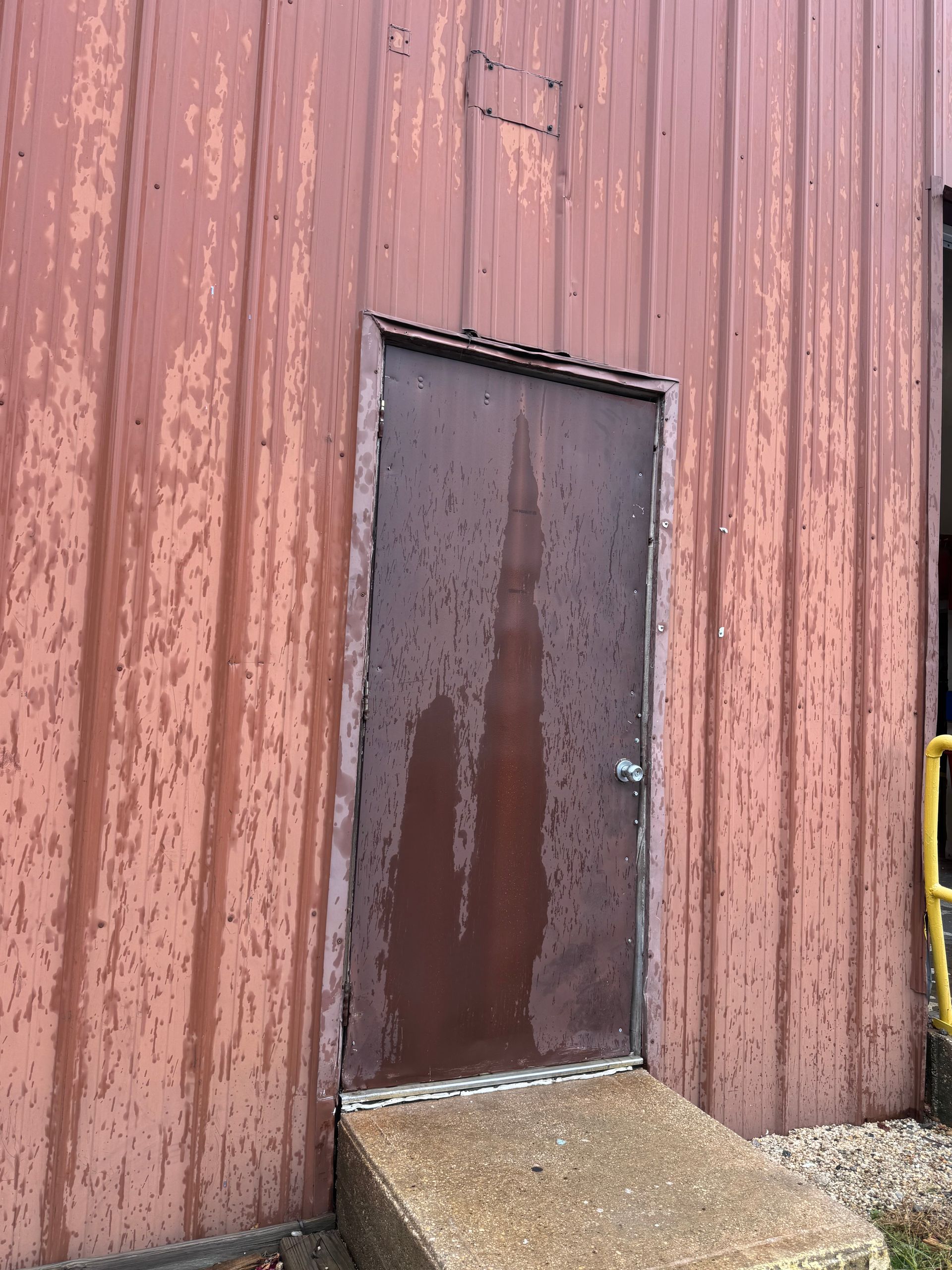 A rusty door on the side of a building