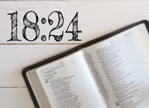 An open bible is sitting on a white wooden table.