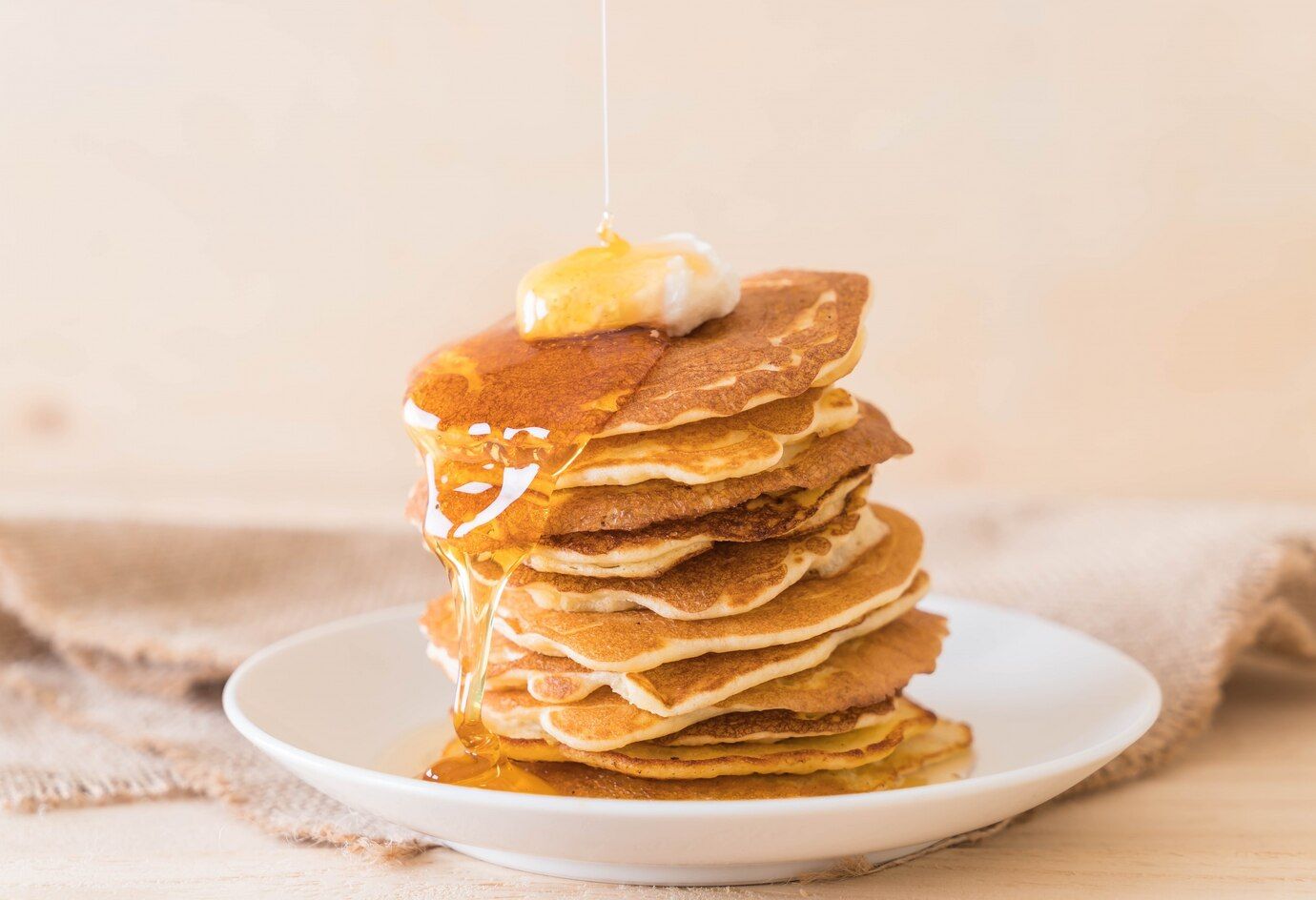 A stack of pancakes with syrup and butter on a white plate.