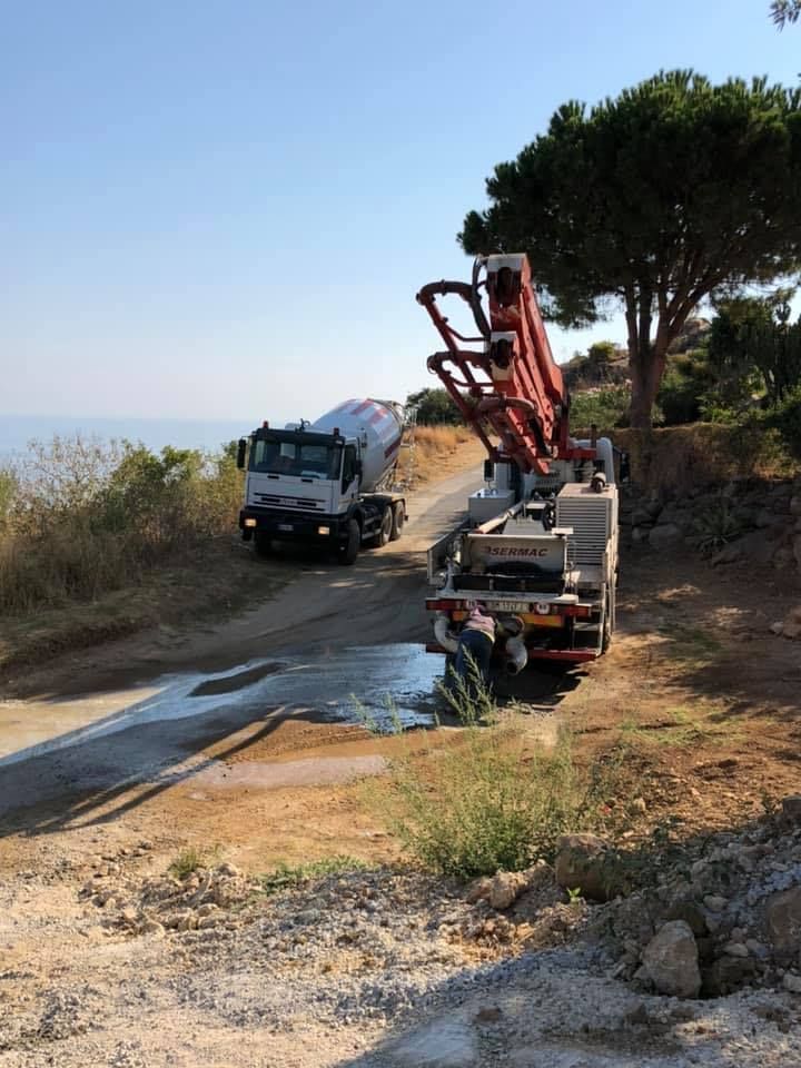 Un camion di cemento sta percorrendo una strada sterrata accanto a un albero.