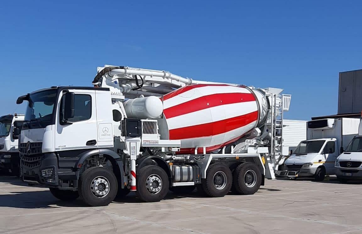 Un camion betoniera rosso e bianco è parcheggiato in un parcheggio.