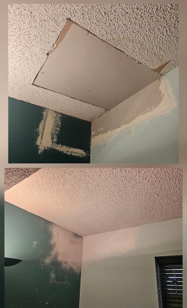 Ceiling with a large section of drywall removed, revealing the space above. Wall is painted green and blue.