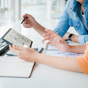 People reviewing a tablet with charts at a bright office desk