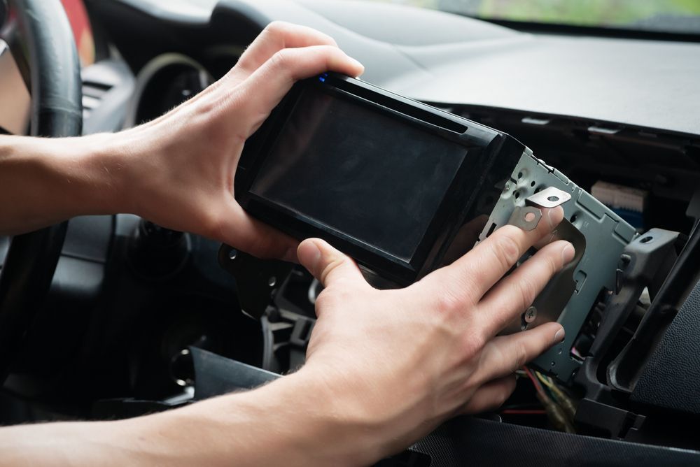 Hands Installing a Car Stereo Unit Into a Dashboard — Mullumbimby Auto Electrical in Brunswick Heads, NSW