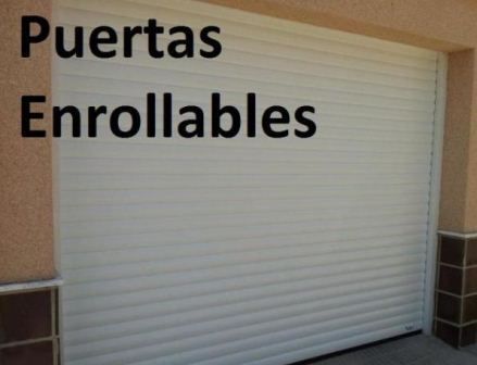 Puerta enrollable blanca en un edificio con el texto “Puertas Enrollables” encima.