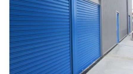 Puertas metálicas azules de un armario de almacenamiento a lo largo de un estrecho pasillo de hormigón.