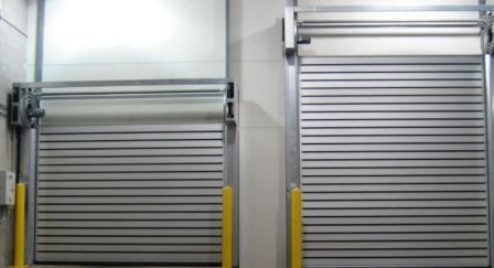 Dos puertas enrollables de metal gris cerradas en un interior industrial.