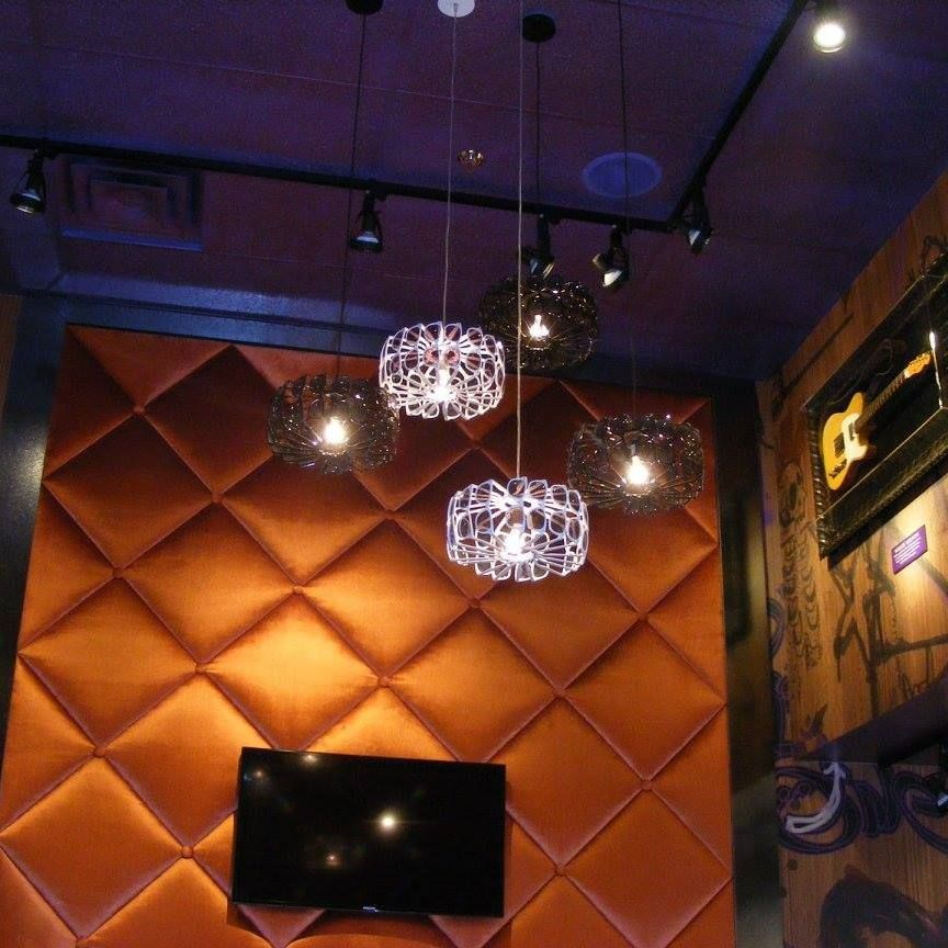 A room with a tv and hanging lights on the ceiling
