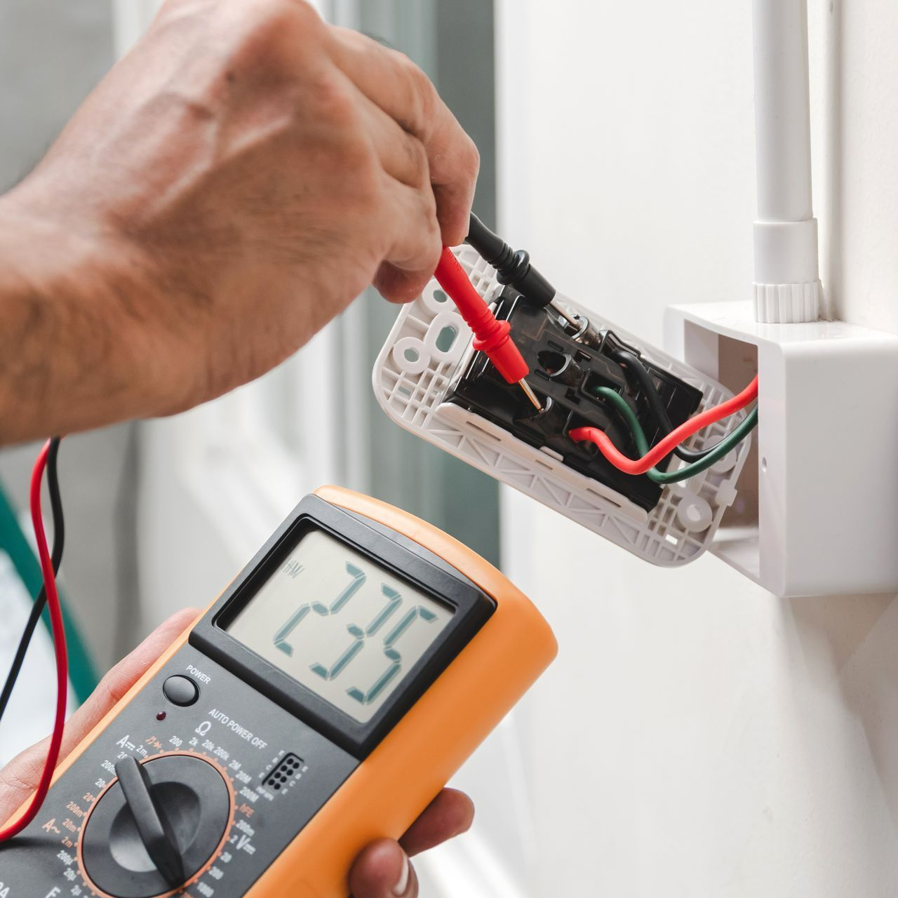 A man is using a multimeter to measure a voltage