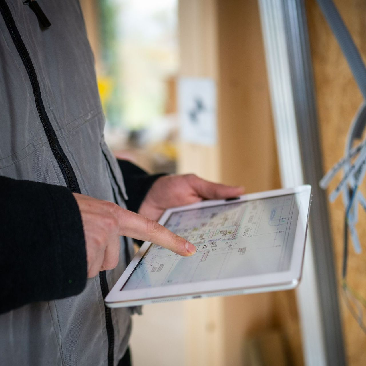 A person is holding a tablet in their hands and pointing at it.