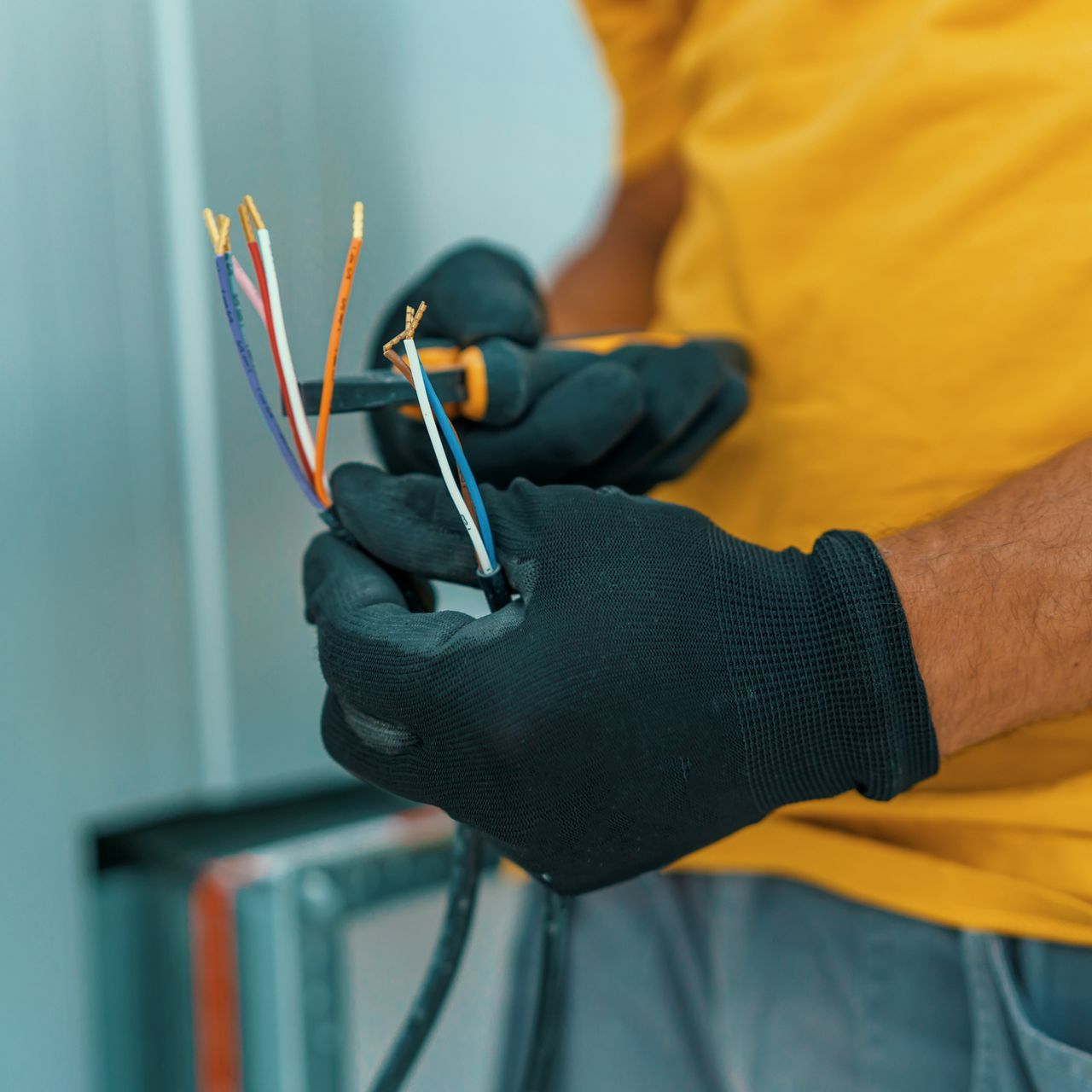 A man wearing black gloves is working on wires