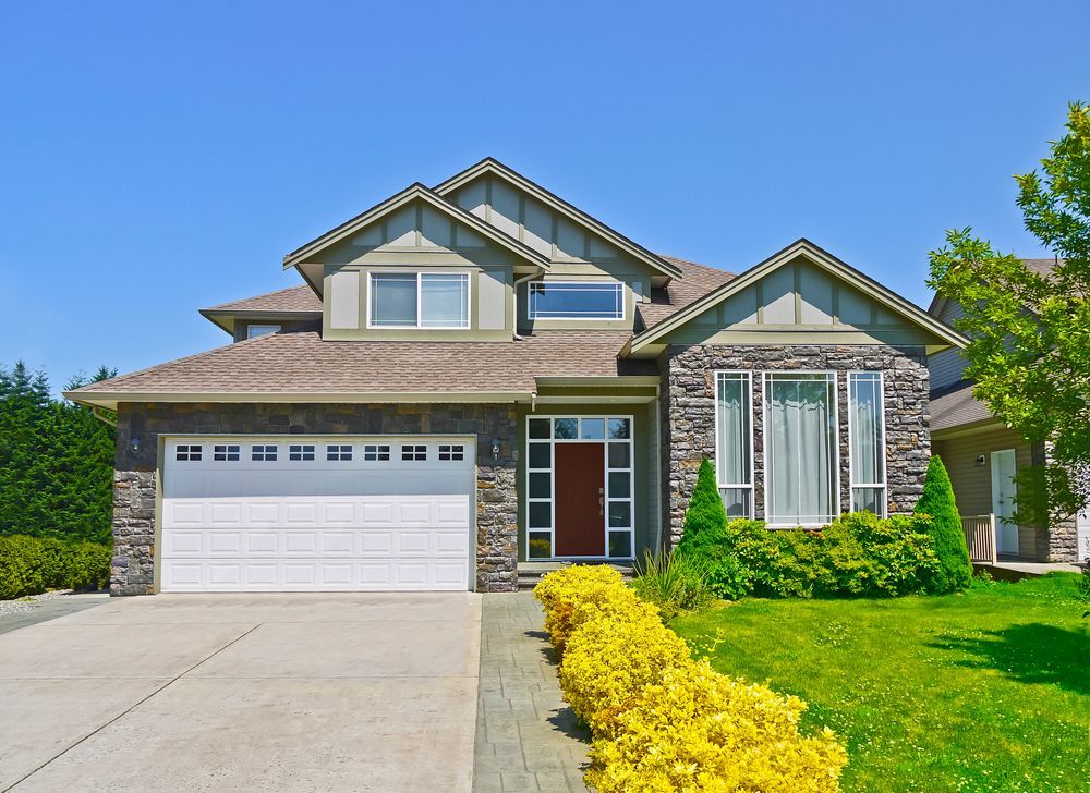 A large house with a white garage door and a red door.