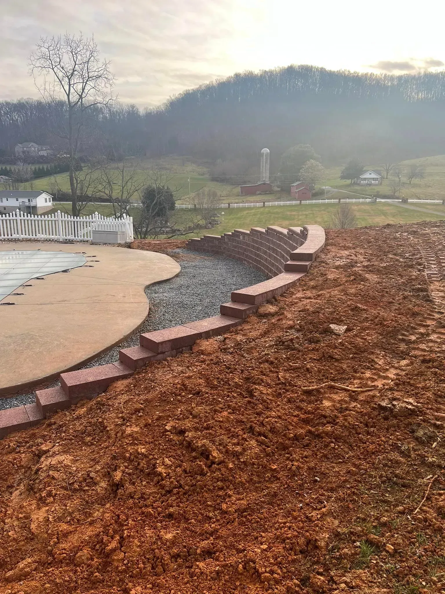 A swimming pool is surrounded by mulch and a fence.