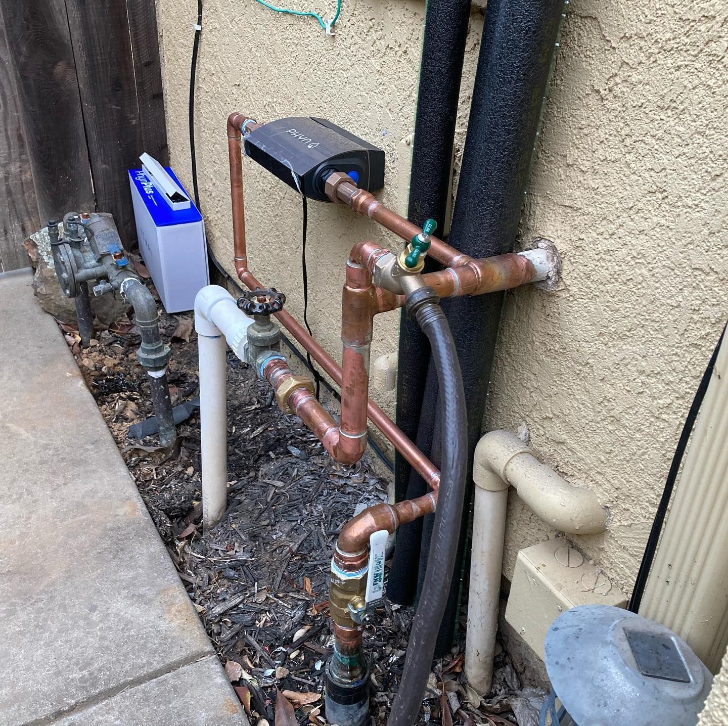 a hose is connected to a copper pipe on the side of a building .
