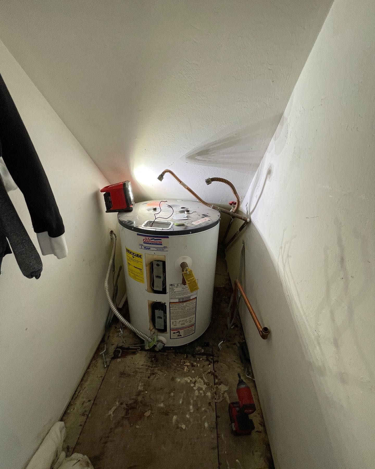 a water heater is sitting in the corner of a room .