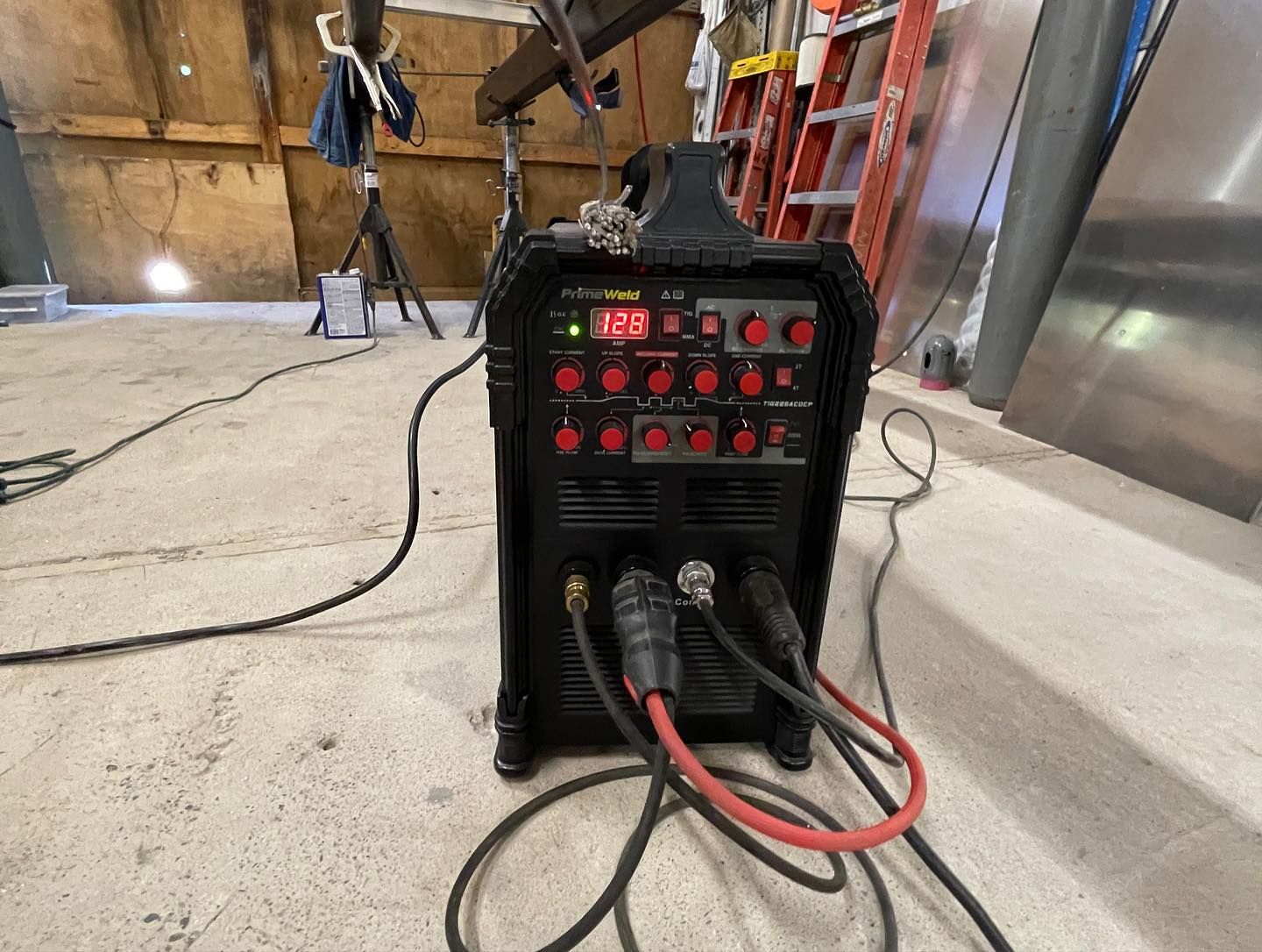 a welding machine is sitting on the floor in a garage .