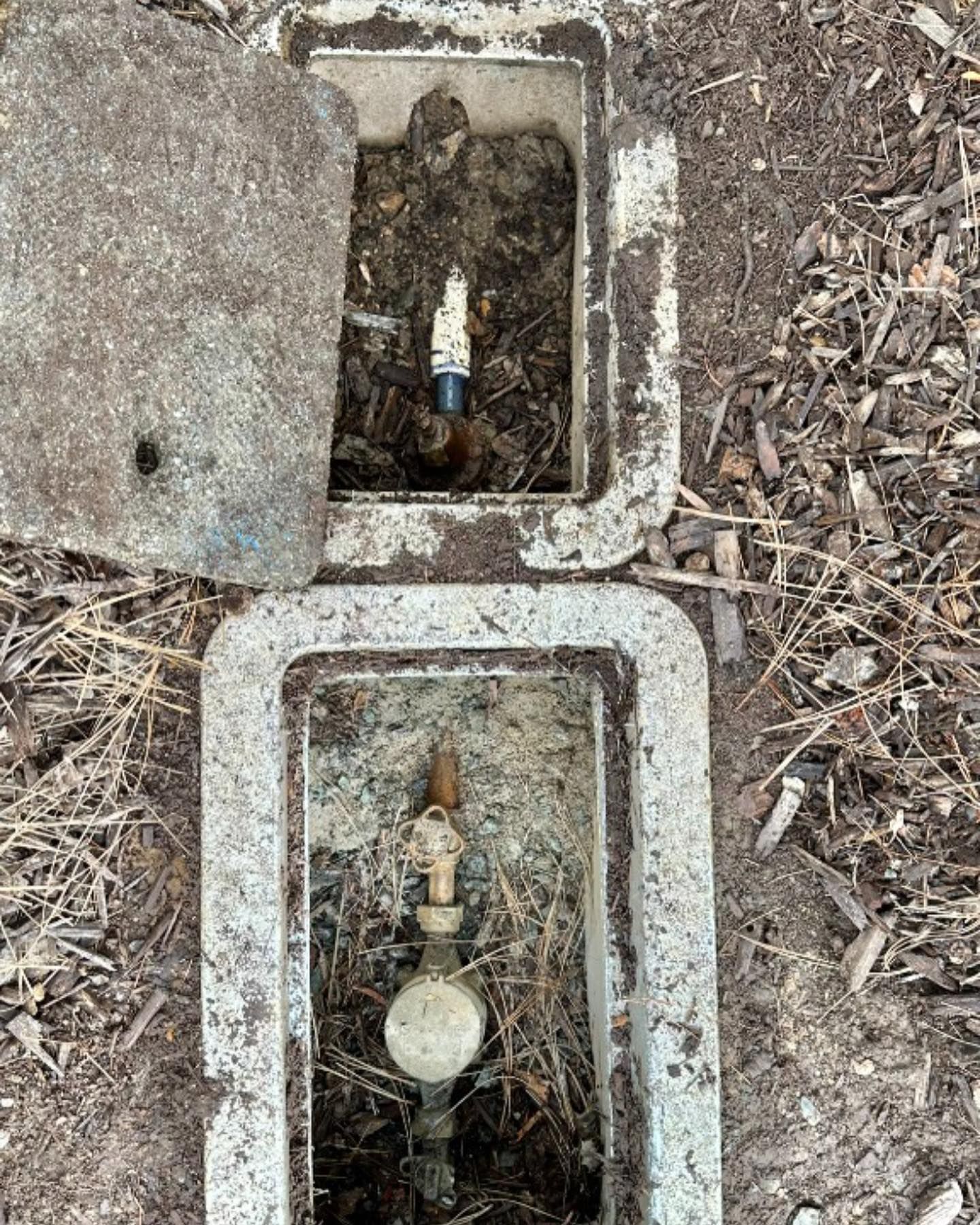 a water meter is sitting in a concrete box on the ground .