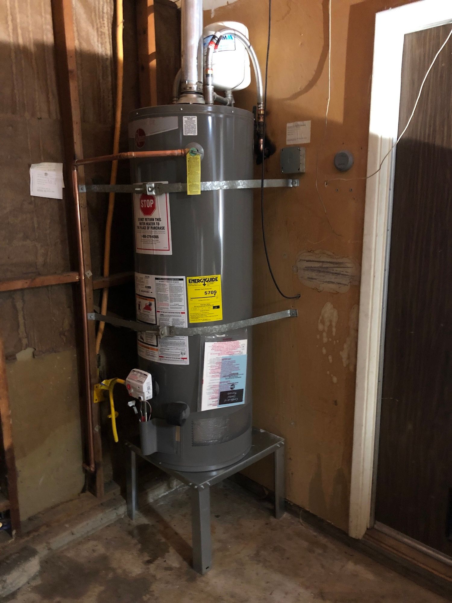 a water heater is sitting in a room next to a door .
