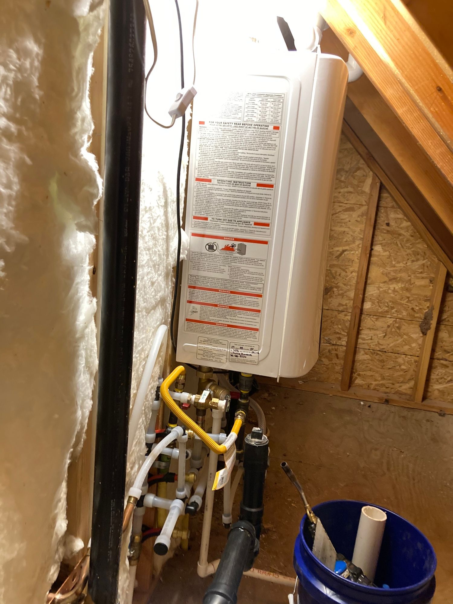 A water heater is sitting next to a pipe in a room.