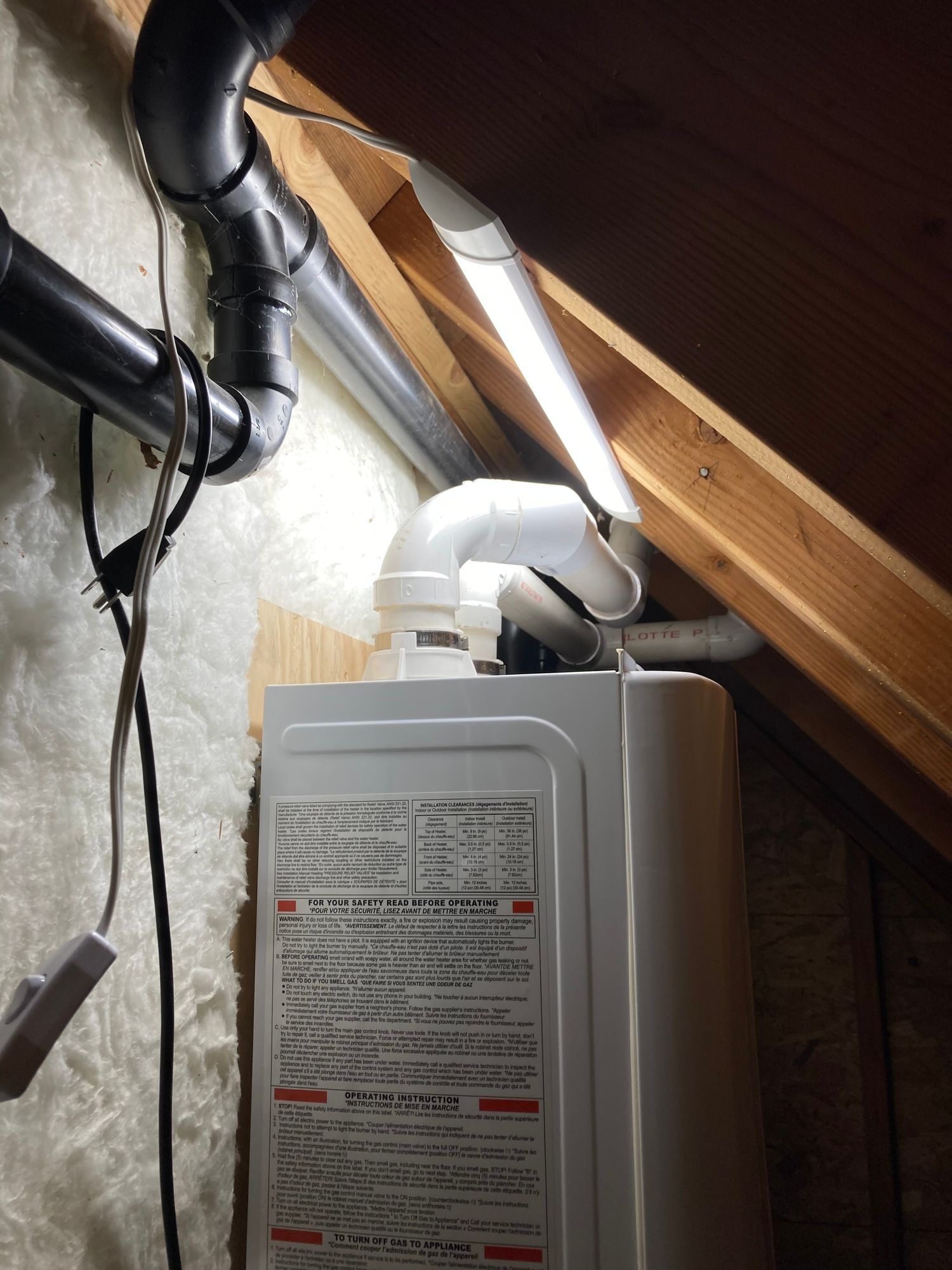 a white water heater is sitting under a wooden ceiling .