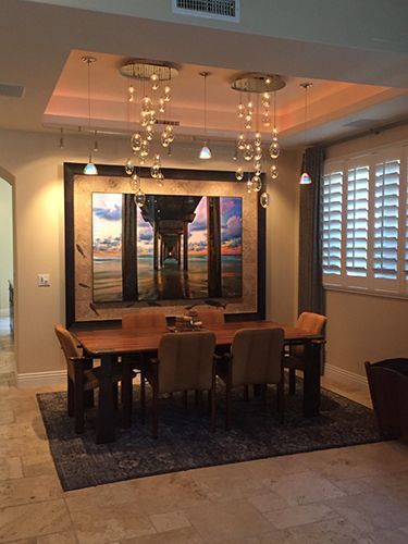 A dining room with a table and chairs and a large painting on the wall.