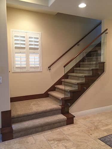 A staircase with a carpeted staircase and a glass railing.
