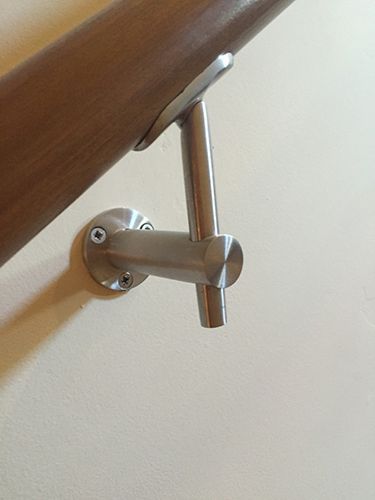 A stainless steel handrail is attached to a white wall.