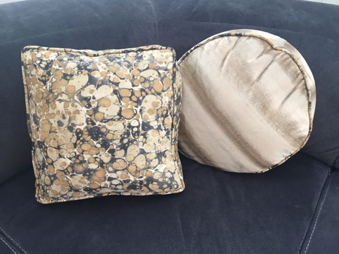 A square pillow and a round pillow are on a couch.