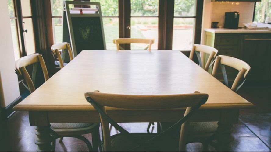 A table and hairs in a room with a large window.