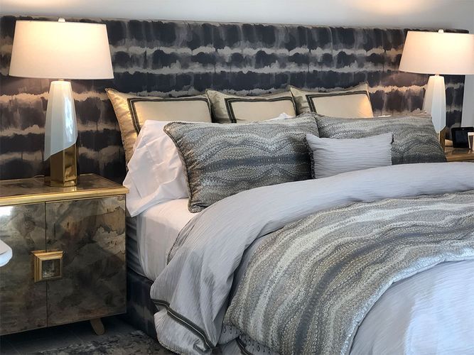 A bedroom with a bed, nightstand, lamps and a headboard
