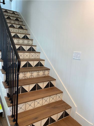 A staircase with black and white tiles on the steps and a black railing.