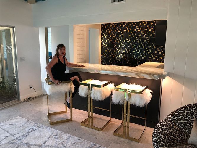 A woman is sitting on a bar stool in a living room.