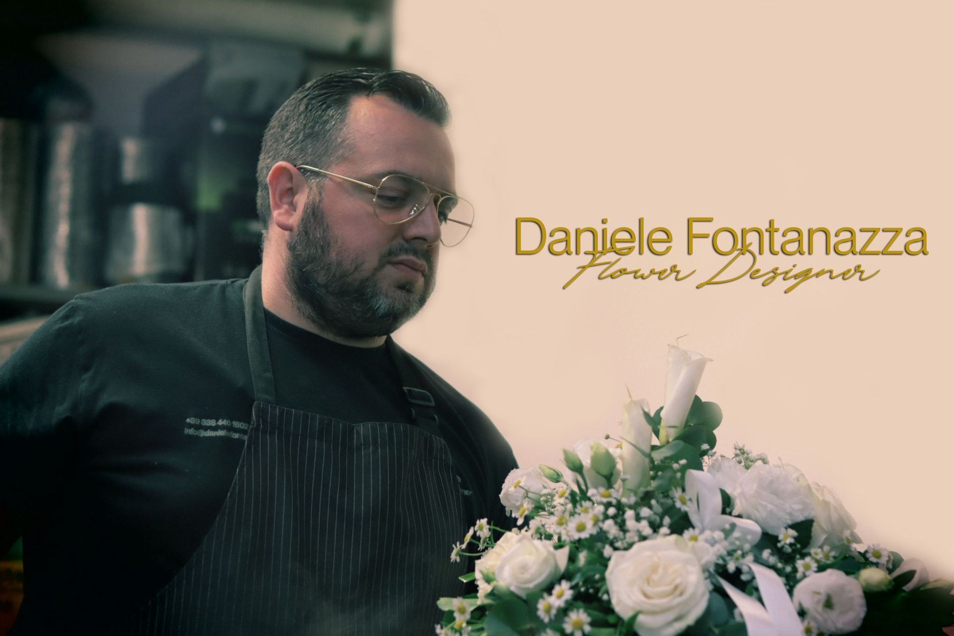 Il flower designer Daniele Fontanazza allestisce fiori bianchi, indossando occhiali e grembiule.