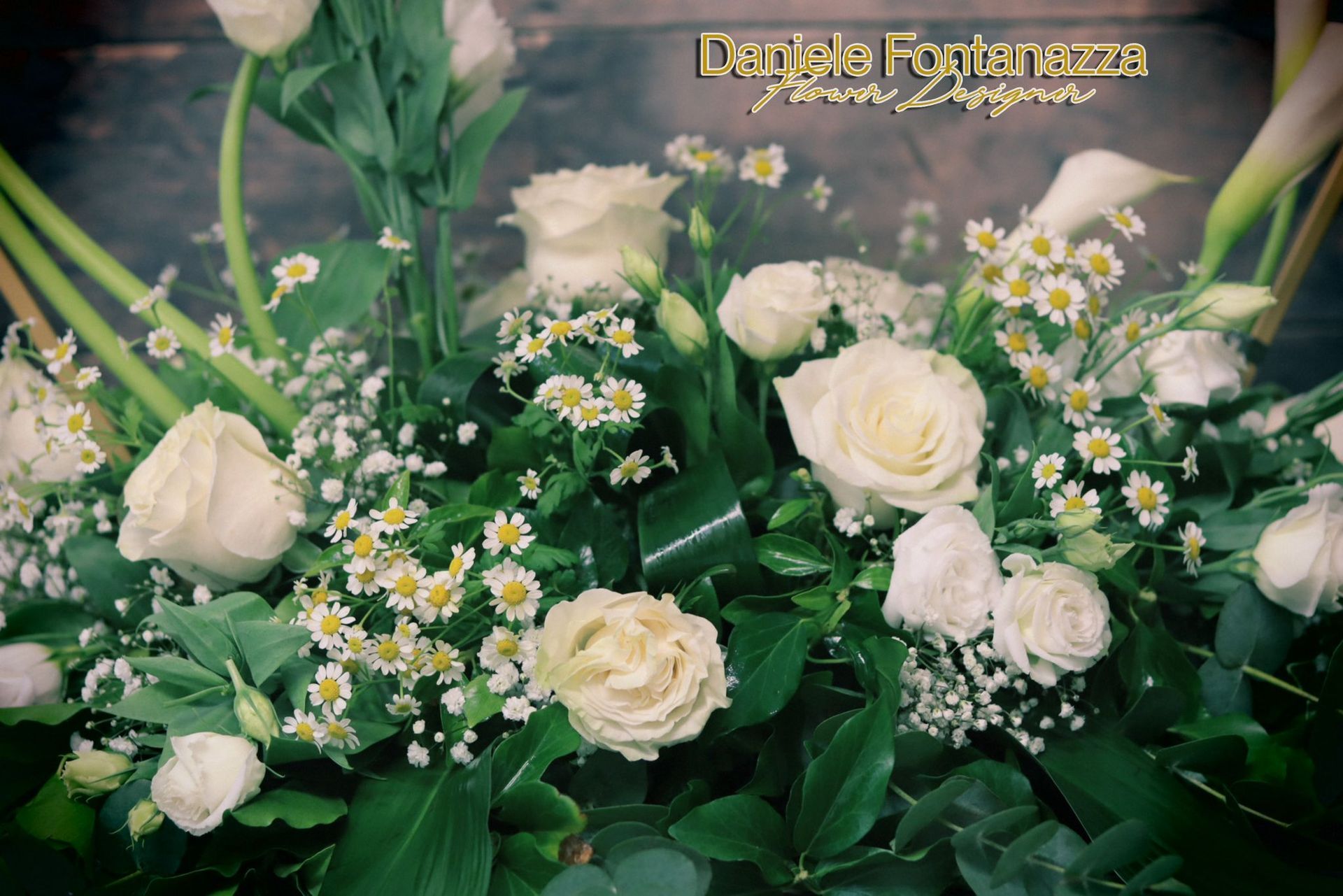 Rose bianche e margherite in una composizione floreale con verde, probabilmente per un'occasione speciale.